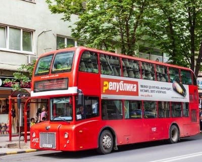 a red double decker bus parked on the side of a street