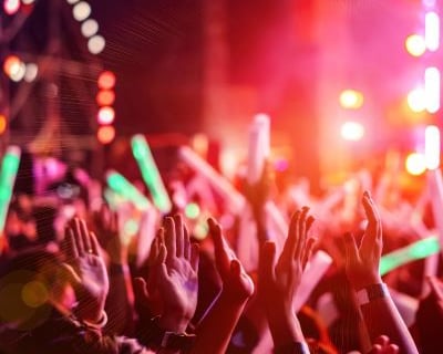 a crowd of people standing in front of a stage with bright lights