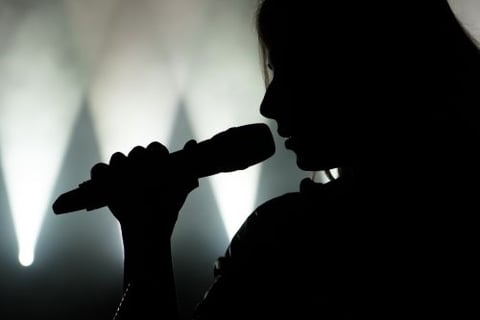a woman singing into a microphone in front of a stage