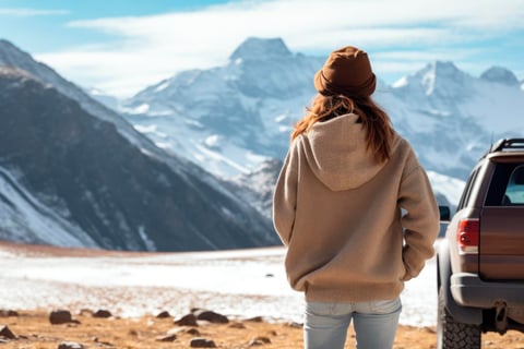 Traveler woman next to her car observing the snowy mountains.