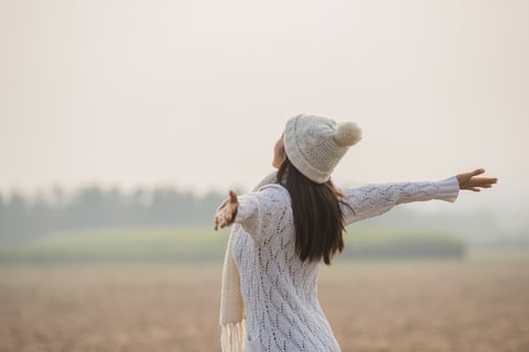 Happy woman enjoying in idyllic nature, celebrating freedom and rising her arms.