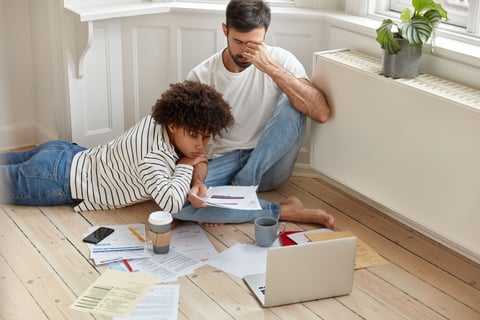 Wife and husband reading foreclosure notice, while sitting on floor.