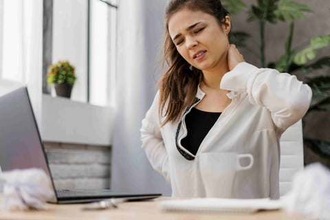 Woman having a neckache while working at home.