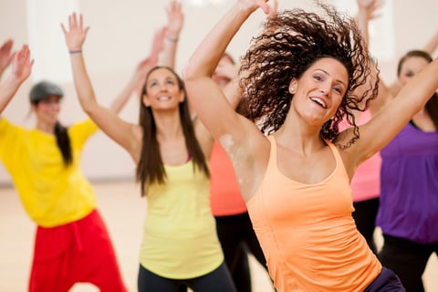 a woman in a bright orange tank top and black pants