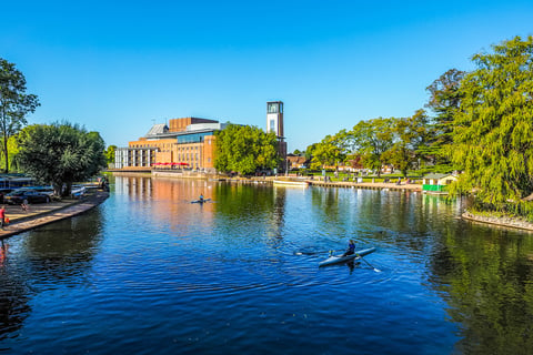 a photo of the Royal Shakespeare Theatre at Stratford Upon Avon with the river Avon in the foreground