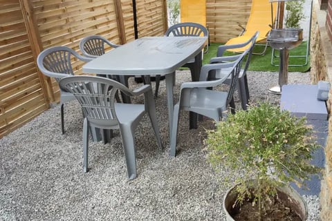 Terrasse ensoleillée avec salon de jardin et parasol. Parfaite pour les repas en plein air. Location de vacances