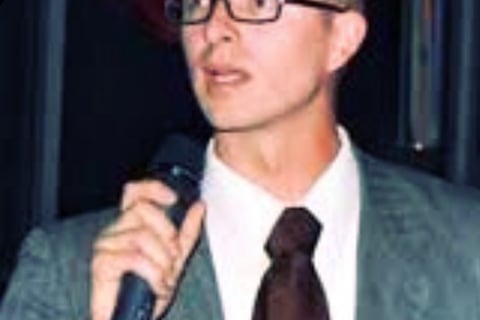Tomkins wearing a suit and giving a speech during a rally in Boise Idaho.