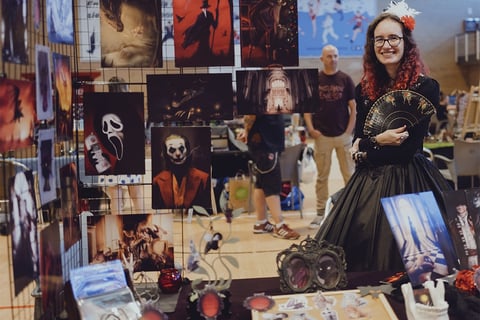 a woman in a black dress standing in front of a display of art