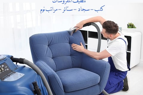 a man is cleaning a blue chair in a living room
