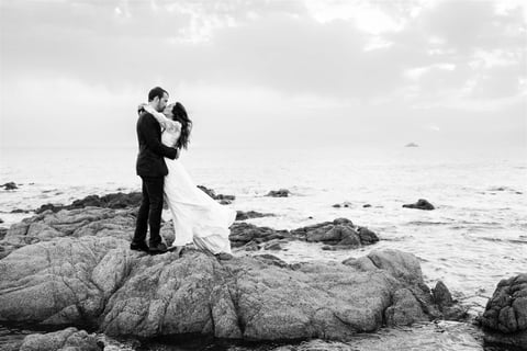 Black and white editorial fine art photo of bride and groom kissing by the sea in South of France