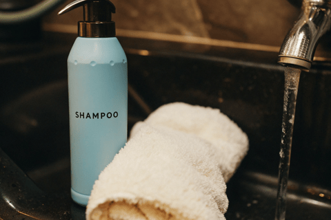 Cat shampoo and a soft towel placed beside a sink ready for grooming.