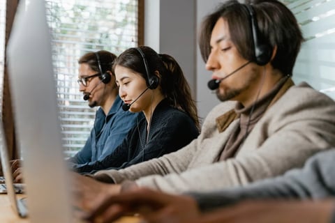 Contact center agents wearing headsets, working in a modern office environment.