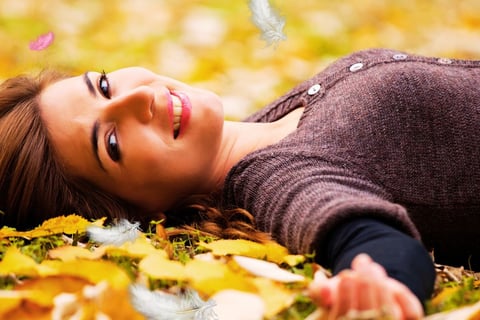 a woman laying on the ground in a field of leaves