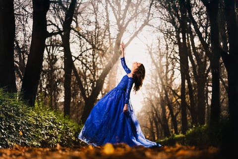 a woman in a blue dress standing in a forest