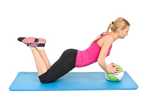 a woman is doing a push-up on a ball
