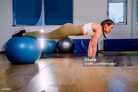 a woman doing push ups on a ball