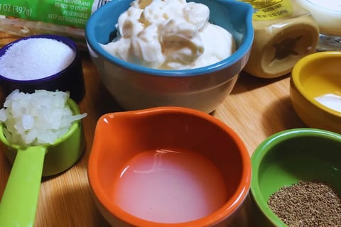 Prepared coleslaw ingredients in individual bowls, ready for mixing