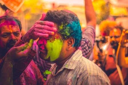 Man celebrating Holi in India with vibrant colors during a trip to India