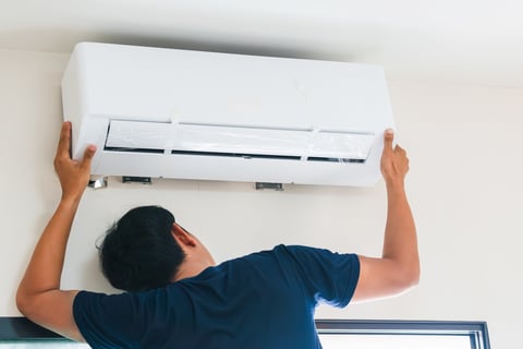 a man is fixing a air conditioner in a room