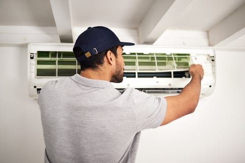 a man in a cap is fixing a air conditioner