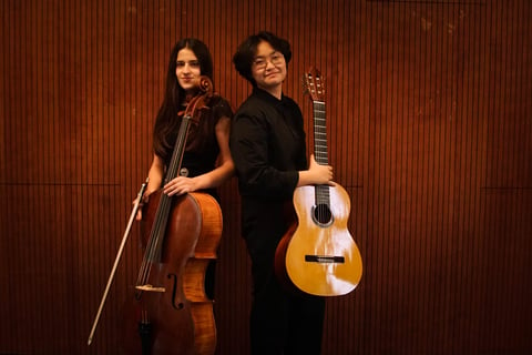 two women holding a guitar and a cello