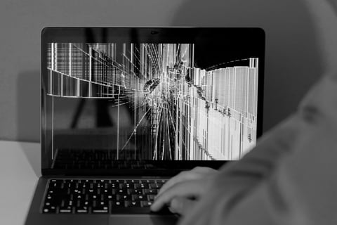 Frustrated person at computer with broken device display, needing expert troubleshooting help