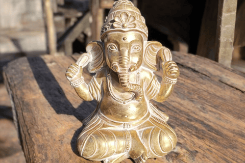 La imagen es una figura decorativa de Ganesha sobre una mesa de madera