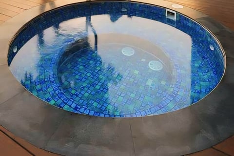 Jakuzzi berbentuk lingkaran dengan keramik roman berwarna biru.