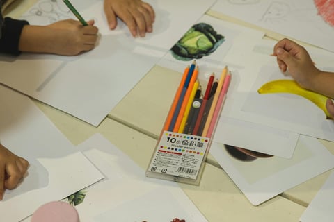 a group of children's hands are drawing on paper