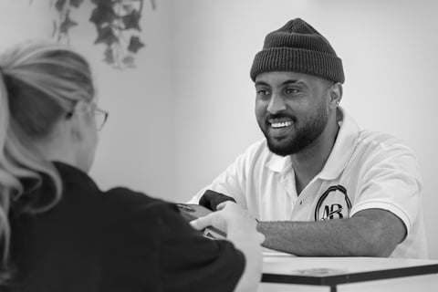 Black and White image of barber tending to customer who wants to pay at the front desk