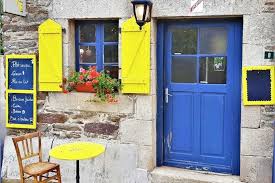 Charming stone-front café with bright yellow shutters and a blue door in Loc-Envel, Brittany, France
