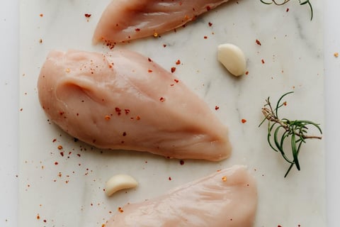 Fresh raw chicken breasts on a wooden cutting board, ready for seasoning and air frying.