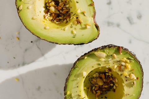 een doorgesneden avocado met zaadjes bestrooid