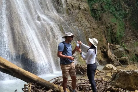 a man and woman standing in front of a waterfall