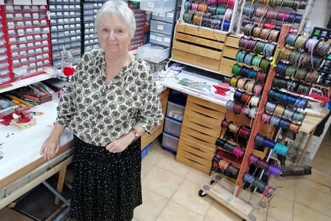 a woman standing in a sewing room with a lot of thread thread spools