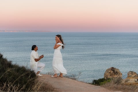 a woman proposing a woman on a cliff overlooking the ocean