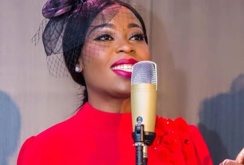Queendalyn Yurglee in a red dress behind a microphone.