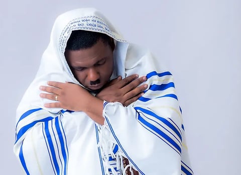 Nacee in a white shirt covered with a stripped blanket.