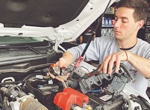 un hombre con una camisa gris está trabajando en un auto