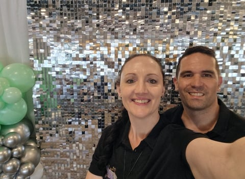 Carly and Kahn in front of silver shimmer wall with mint silver and white balloon garland at the Fiction Bar Cleveland