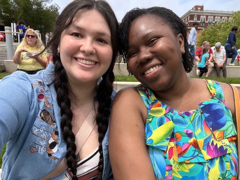 two women sitting next to each other in front of a crowd smiling