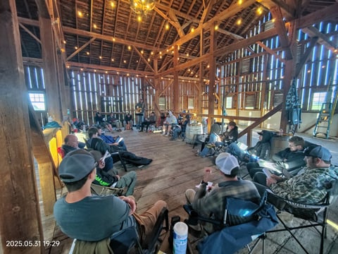 a group of people sitting in chairs in a barn