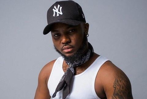 King Promise in a black cap in a singled with a black bandana around his neck.