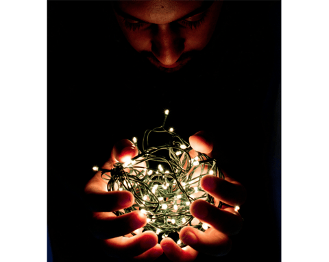 Man holding bundle of fairy lights, symbol of self-reflection