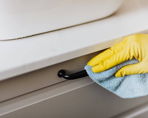 dusting a bathroom cabinet during home cleaning service