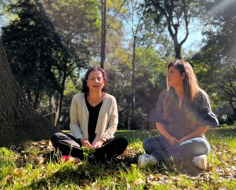 Fundadoras de Alianzas Ancestrales sentadas sobre un pasto verde, con árboles al fondo, transmitiend