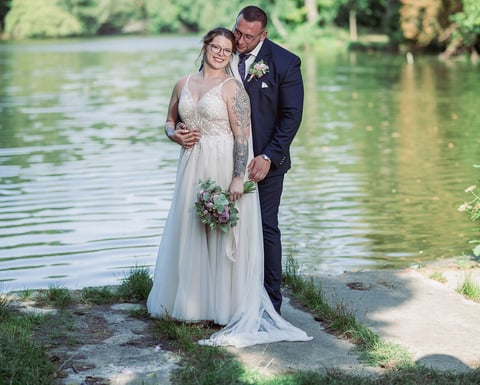a bride and groom standing in front of a lake