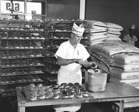 Cooper Donuts - Mr. Richard Evans glazing chocolate donuts.