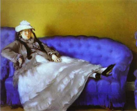 a woman in a white dress and hat sitting on a blue couch