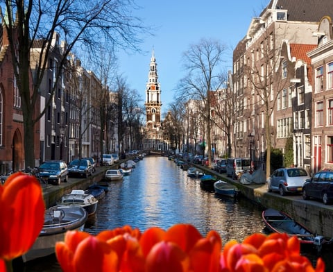 amsterdam - a canal with boats and a church steeple